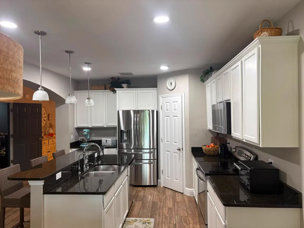 After: the same kitchen and island with every cabinet painted bright white
