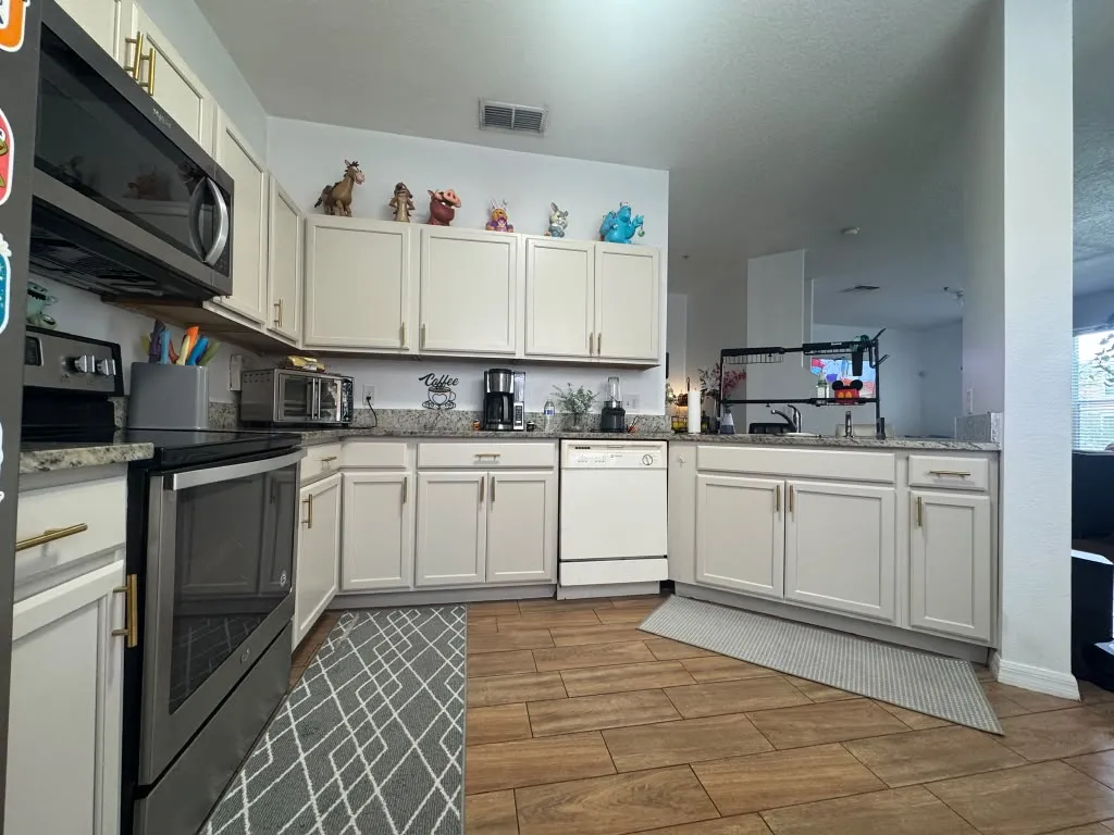 Full kitchen with cabinets painted soft cream and brass pulls