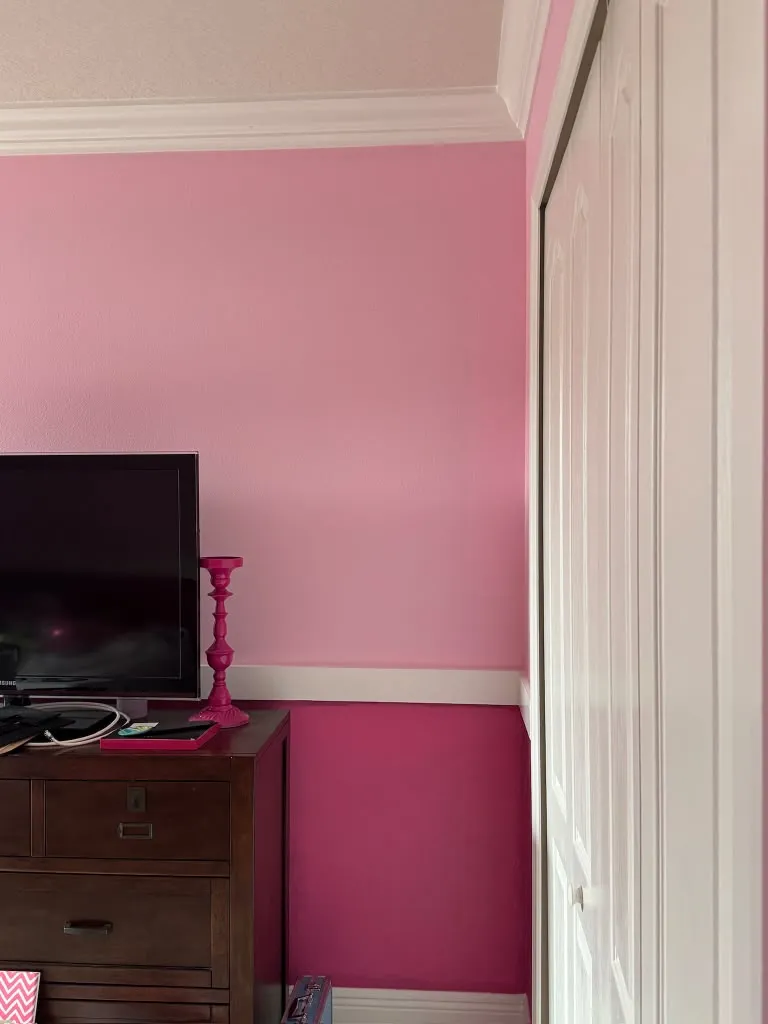 Two-tone pink bedroom where the light and dark pink meet at a white chair rail