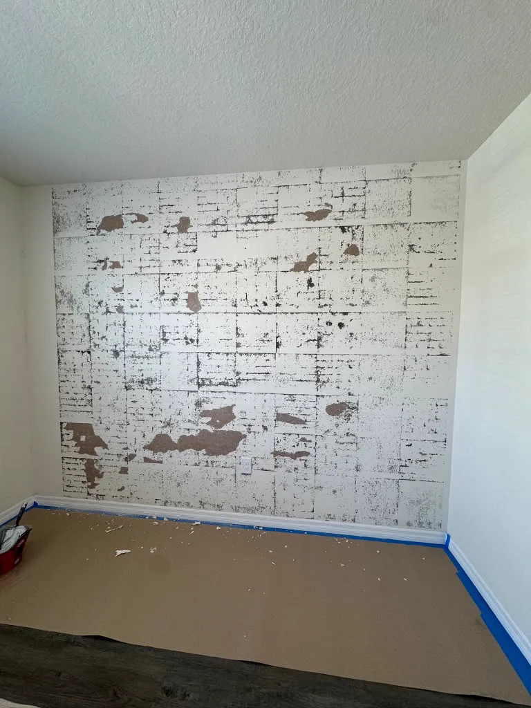 A wall covered in old adhesive and torn paper before repair