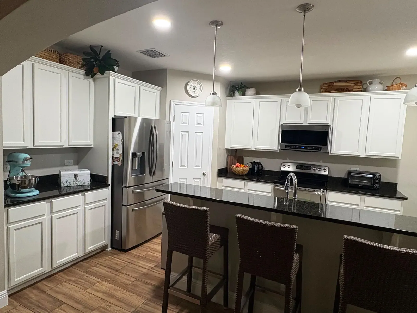 A kitchen in Ocoee, FL after we painted the cabinets bright white, with a black granite island