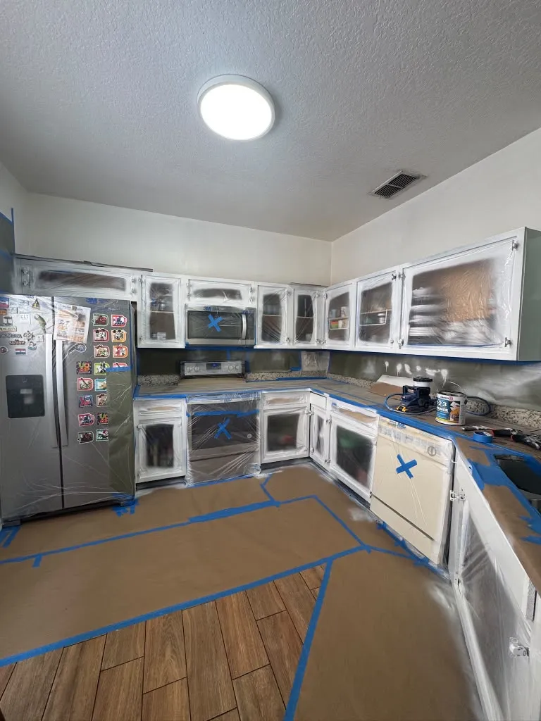 Kitchen wrapped in plastic with the floor papered and taped before painting