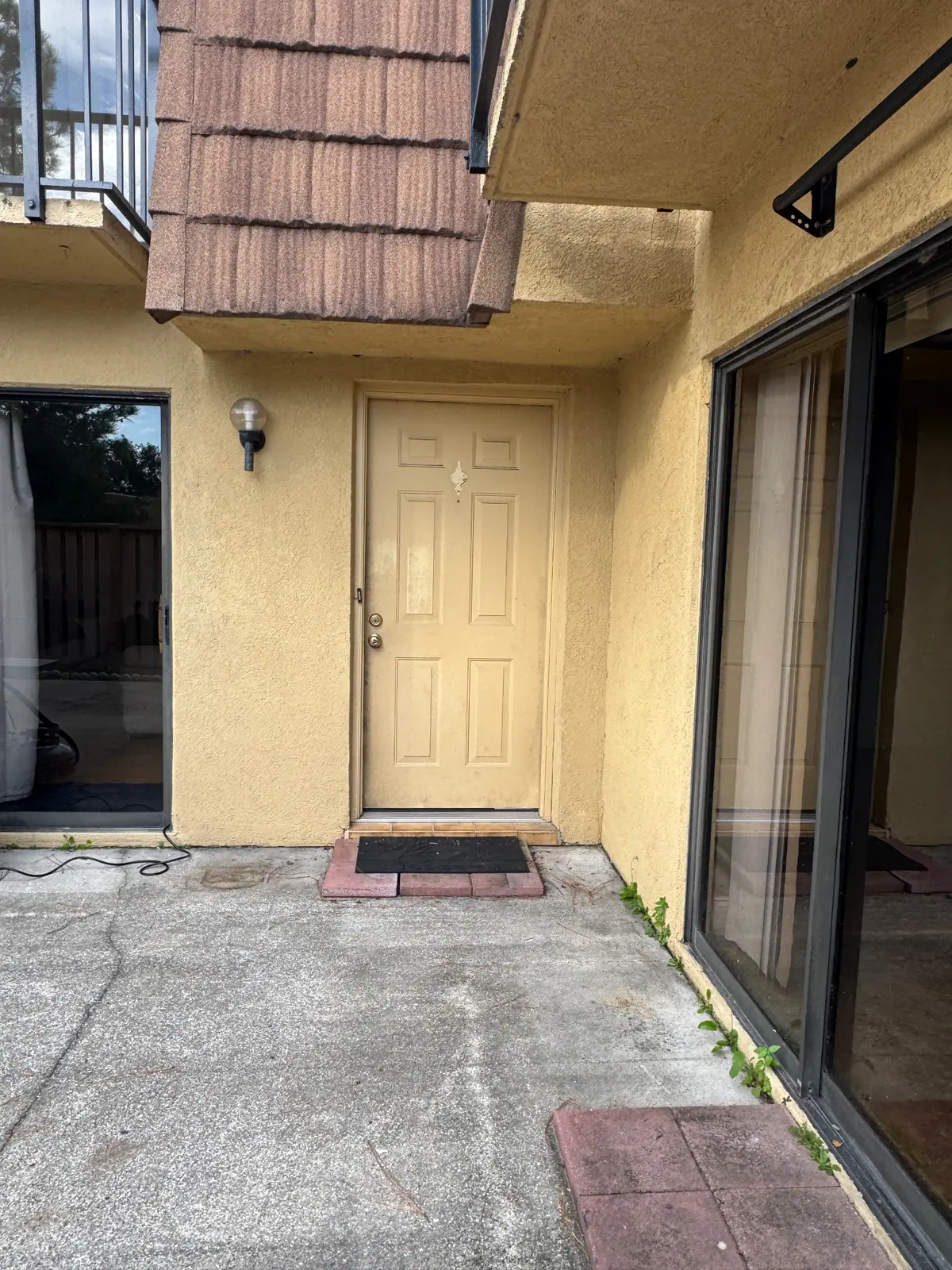 Faded tan entry door in a stucco courtyard before painting