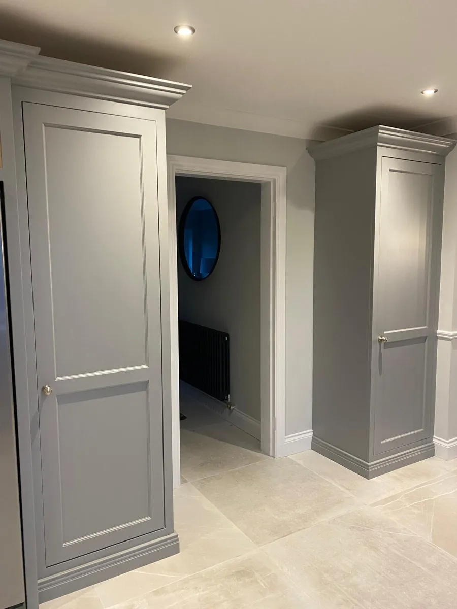 Two tall cabinets painted grey on each side of a doorway