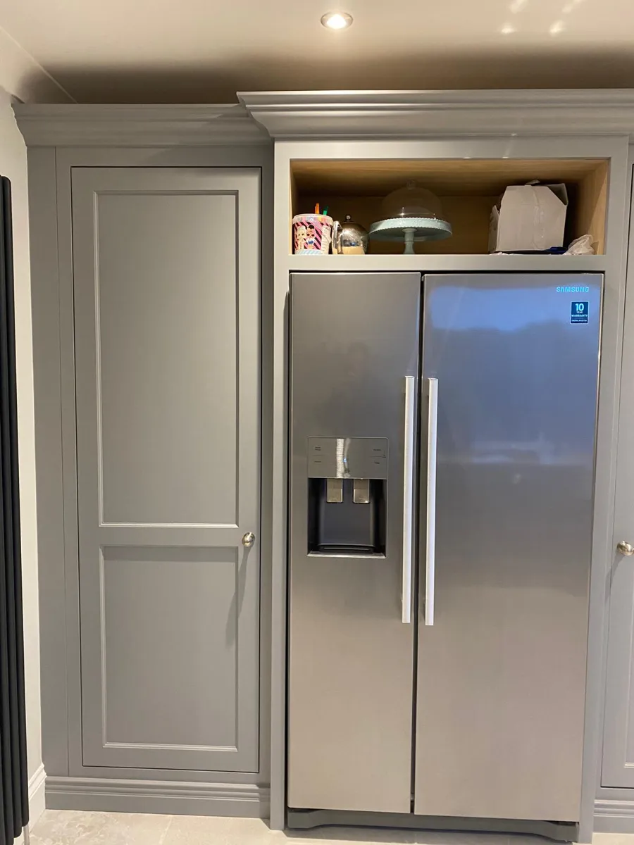 Tall units painted grey around a steel fridge