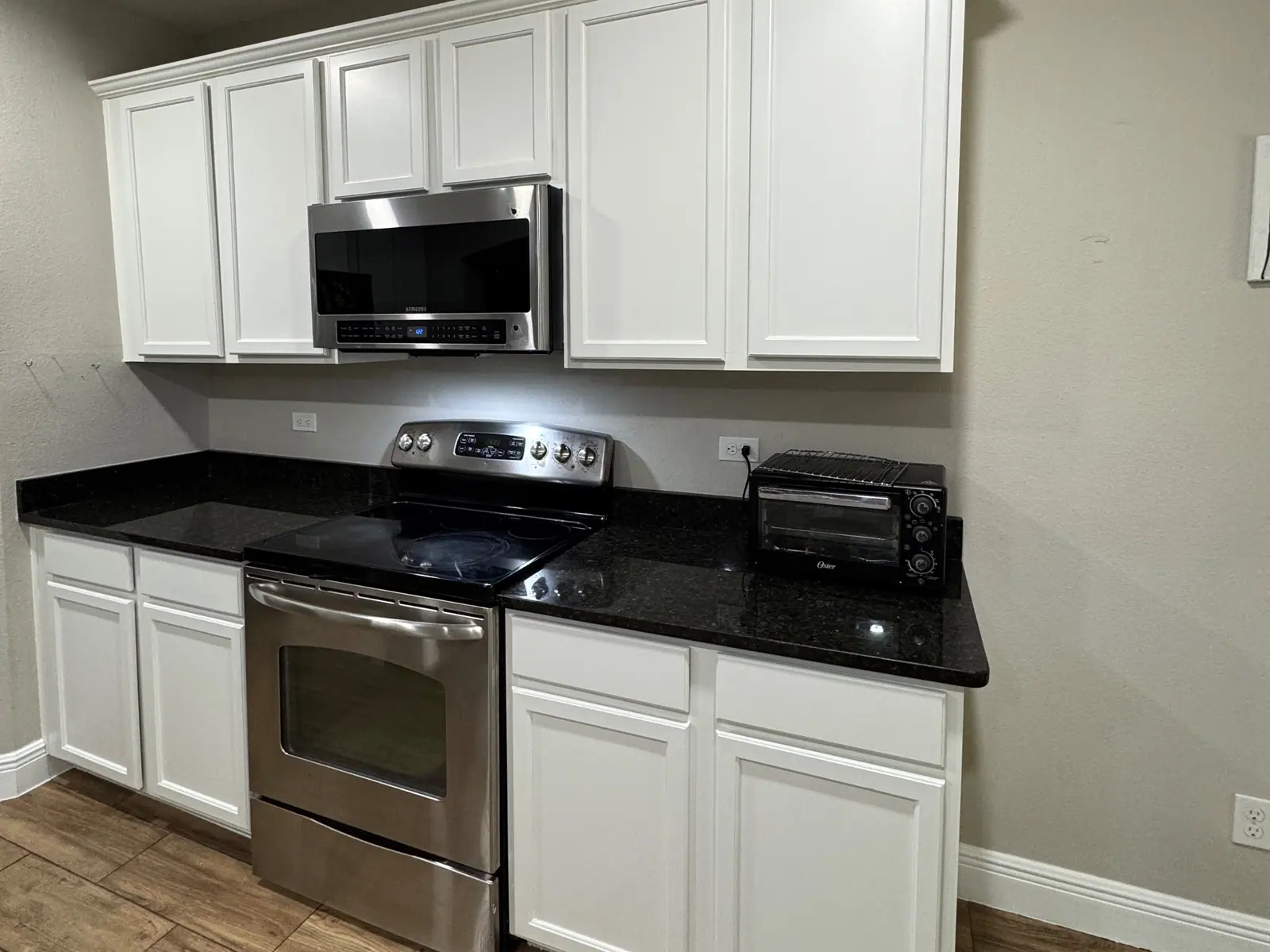 White cabinets around a stainless range and black granite