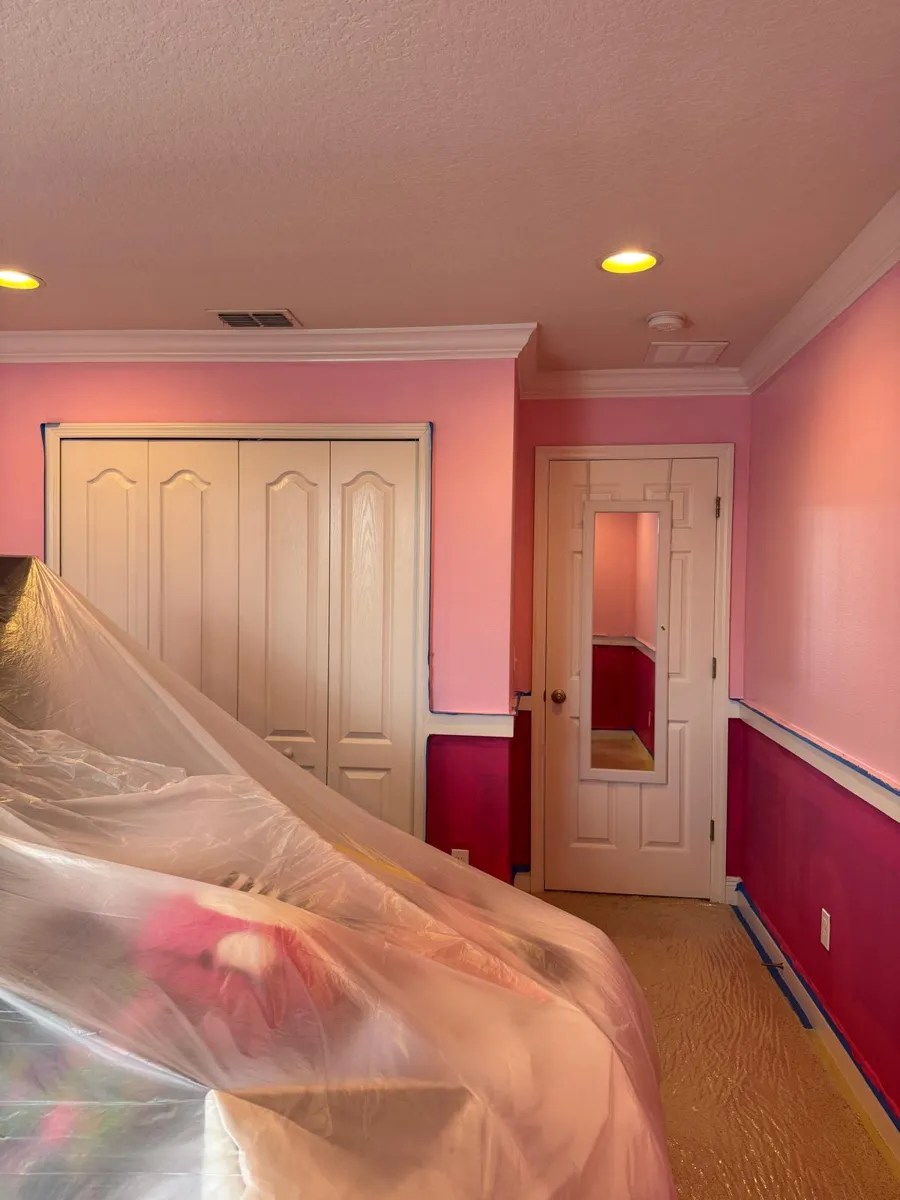 Closet wall with pink above and magenta below, the bed still under plastic